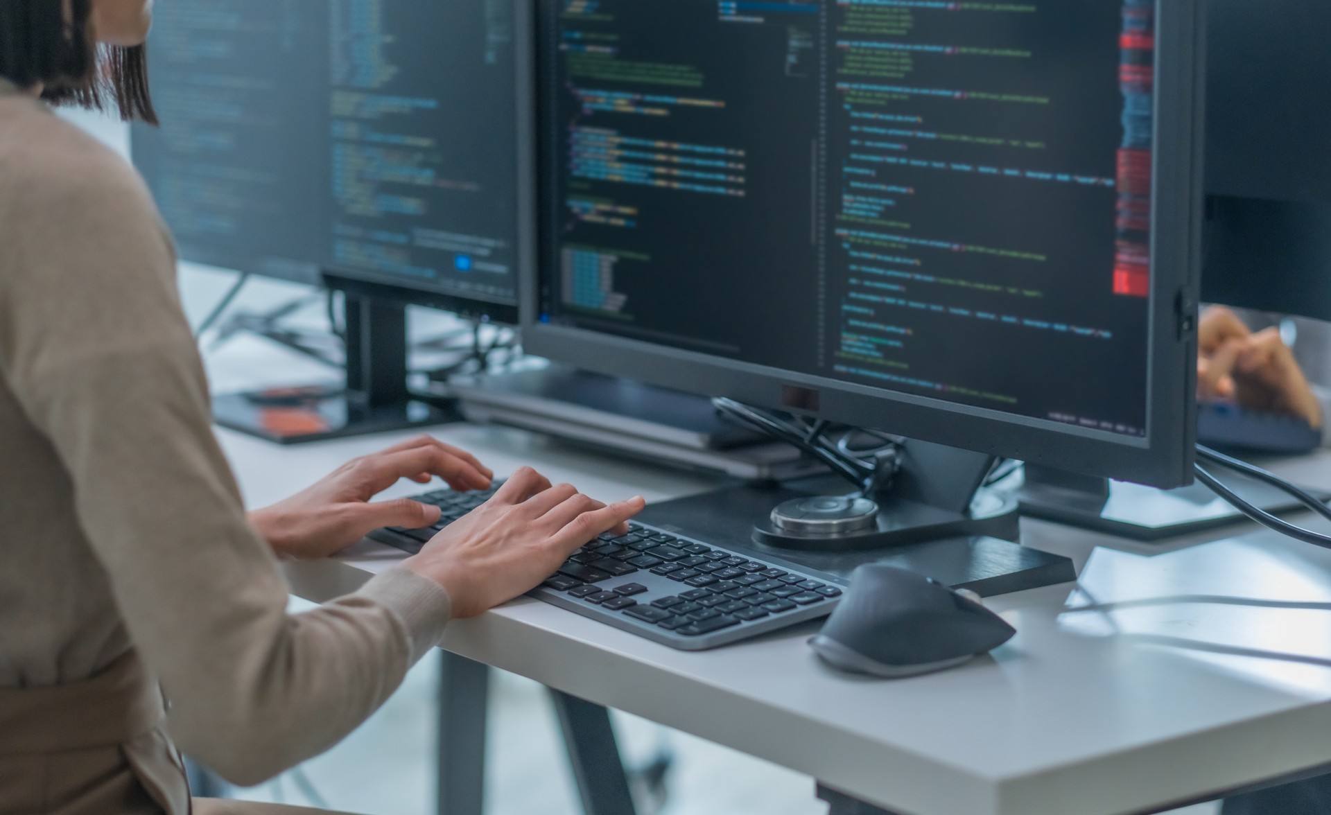 close up hand of Asian prompt engineer developer coding app with software data sitting in front of computer monitor at office